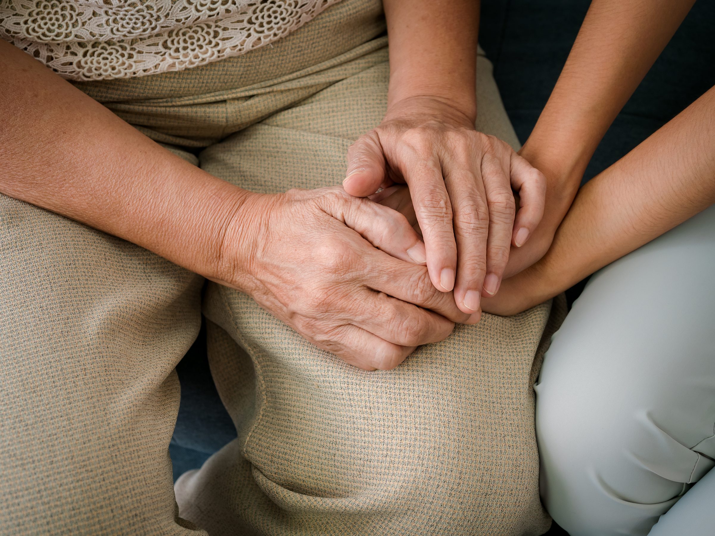An older woman’s hands holding the hands of a younger family member